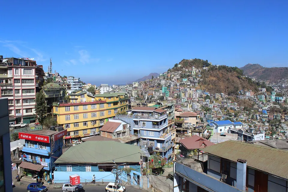 Aizawl's colourful buildings stacked along a steep ridge under a clear blue sky, Mizoram