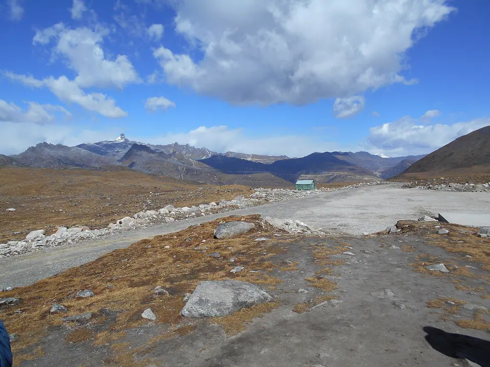 Wide high-altitude valley with brown grass and a road leading to Bum La Pass, Tawang