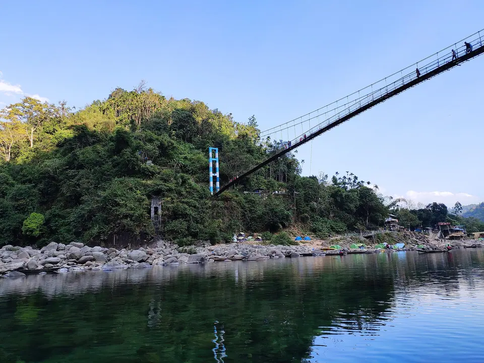 The Dawki suspension bridge crossing the Umngot River between forested banks