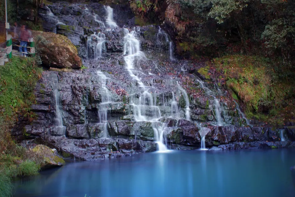 Thin streams of Elephant Falls tumbling down black rock ledges into a turquoise pool