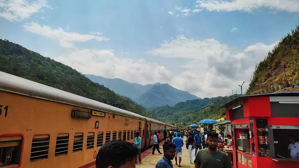 A train at New Haflong station on the hill railway, with forested Dima Hasao hills behind