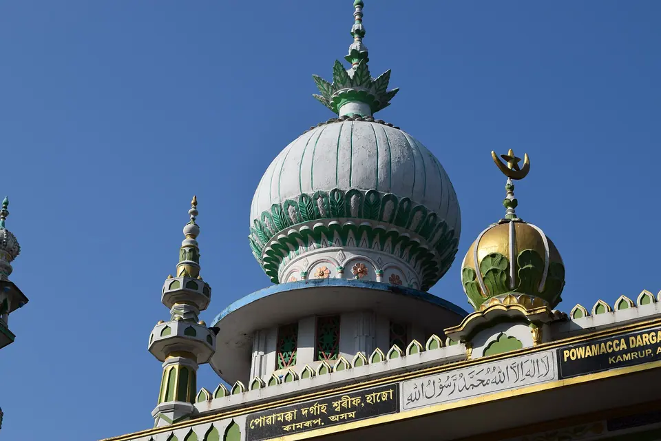 White and green domes of the Powa Mecca shrine against a deep blue sky at Hajo