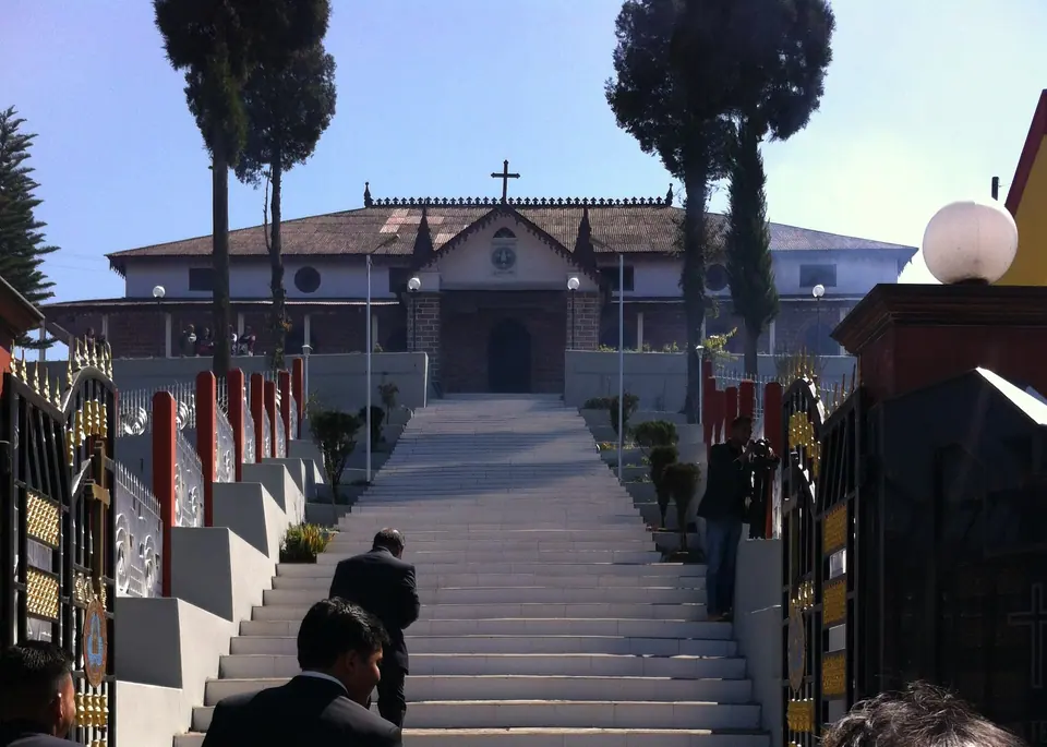 Steps leading up to the white Presbyterian church in Jowai, flanked by tall conifers