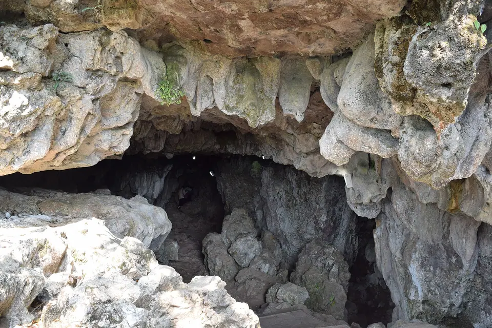 Pale limestone formations framing the dark entrance passage of Mawsmai Cave near Sohra