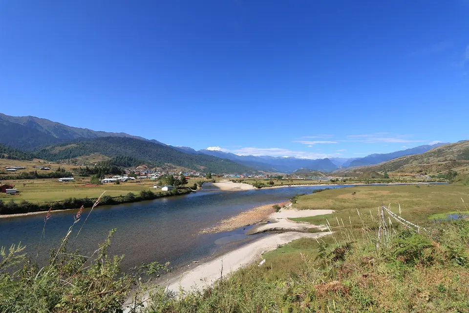 The Siyom river curving through open grassland toward the mountains of Mechuka