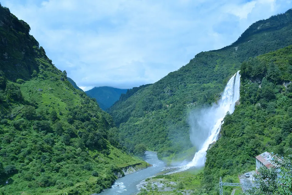 Nuranang (Jang) Falls plunging down a green mountainside into a turquoise river valley near Tawang