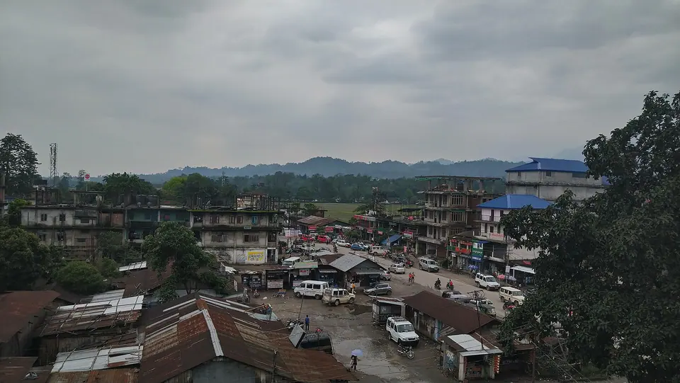 Rooftops and a busy market street in Pasighat town under grey clouds