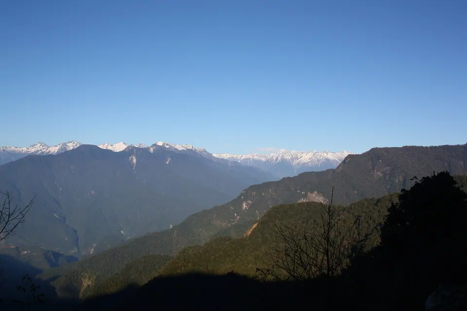Snow-capped tops of the Mishmi Hills beyond forested ridges, seen from Mayodia Pass above Roing