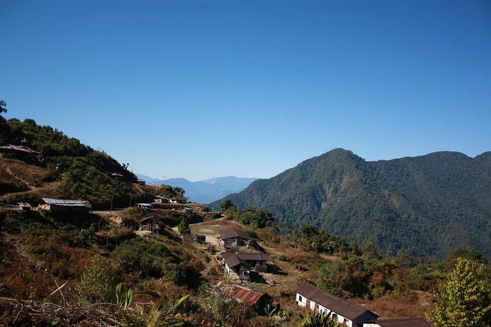 A small settlement of tin-roofed houses on a hillside along the Roing–Mayodia road