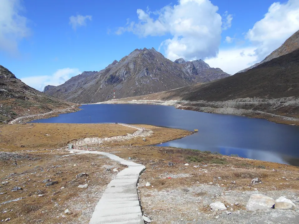A boardwalk leading along blue Sela Lake below rocky peaks at Sela Pass, 4,170 m, Arunachal