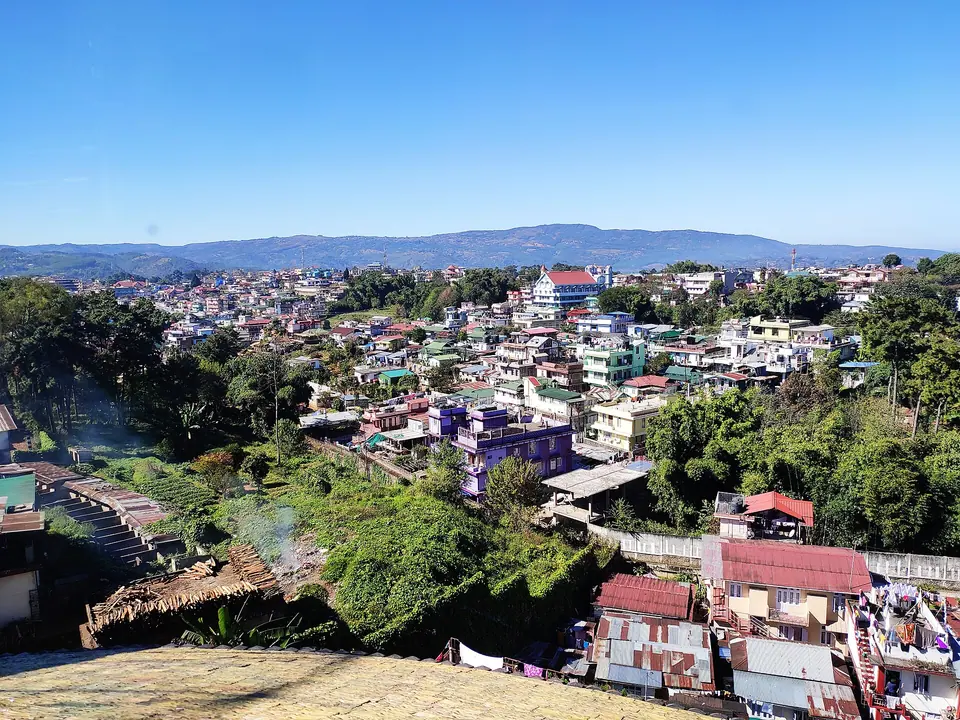 Colourful houses of Shillong spread over green hills under a clear blue sky, seen from Mawlai