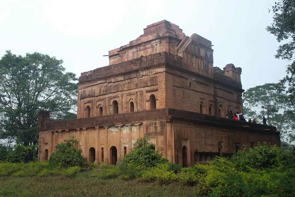 The tiered red-brick Kareng Ghar palace of the Ahom kings rising above trees near Sivasagar