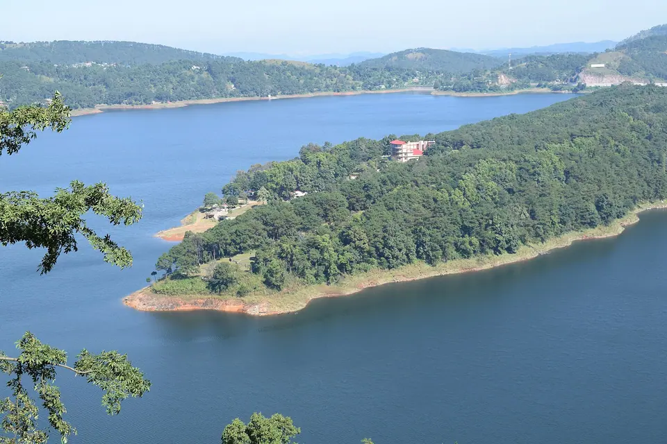 Umiam Lake reservoir seen from above, a long wooded peninsula reaching into deep blue water