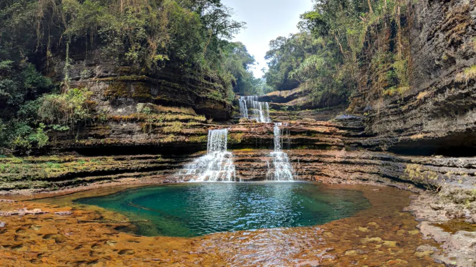 Wei Sawdong's stepped falls spilling into a round turquoise pool in a sandstone gorge near Sohra