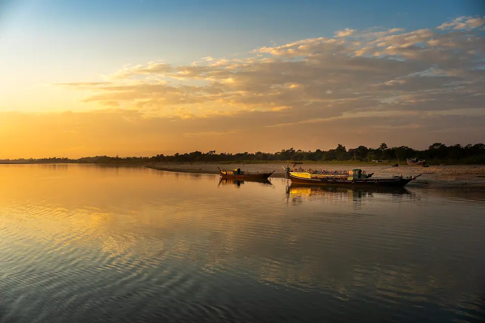 Golden dusk light on the Brahmaputra at Majuli, with wooden ferry boats moored at the shore