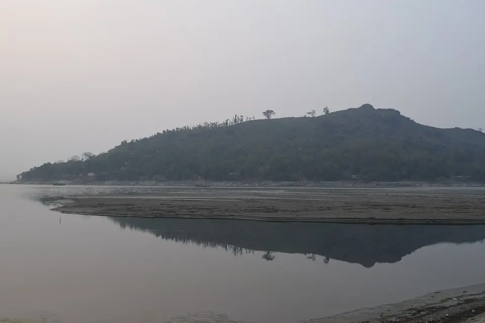 A forested hill mirrored in the still Brahmaputra near Baghbar, Barpeta, Assam